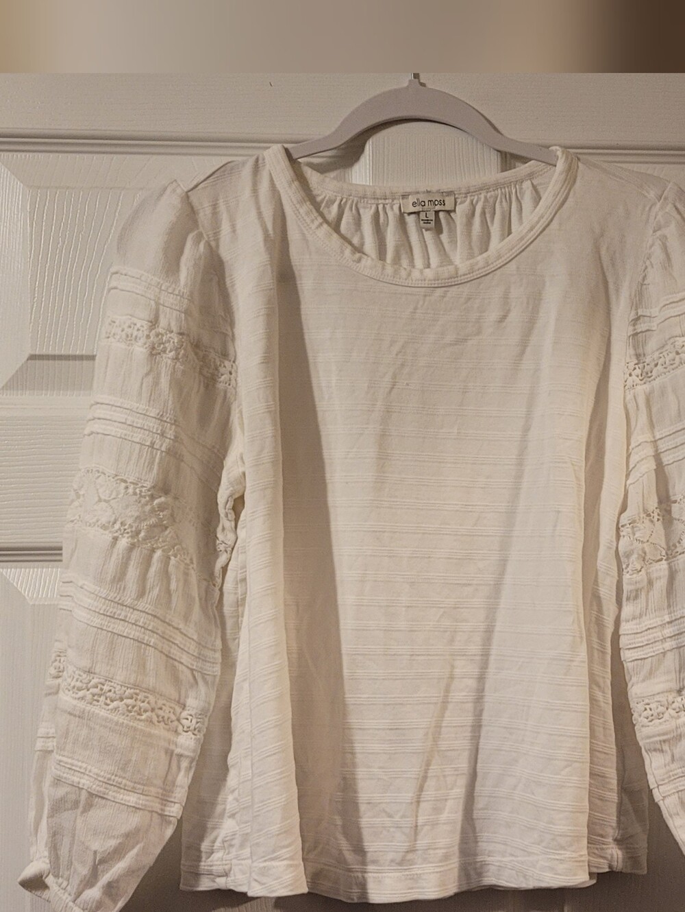 White long-sleeve cotton top featuring delicate lace trim details on the sleeve
